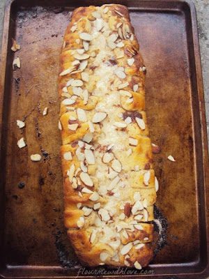 Macaroon-Cinnamon-roll-braid-cinnamon-rolls-wrapped-around-a-coconut-cream-cheese-center,-topped-with-almonds-and-drizzled-with-icing.