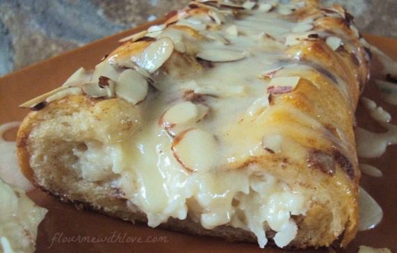 Macaroon-Cinnamon-roll-braid-cinnamon-rolls-wrapped-around-a-coconut-cream-cheese-center,-topped-with-almonds-and-drizzled-with-icing.